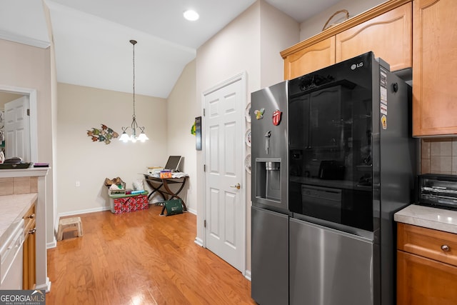 kitchen with stainless steel fridge with ice dispenser, light wood finished floors, light countertops, decorative backsplash, and vaulted ceiling