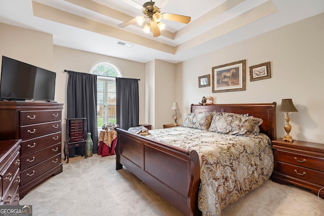 bedroom with light colored carpet, a tray ceiling, and a ceiling fan