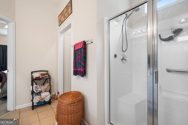 full bath with a stall shower, tile patterned flooring, and baseboards