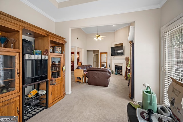 living room with light colored carpet, ornamental molding, a ceiling fan, and a fireplace