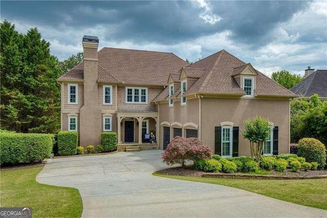 view of front facade with a chimney, stucco siding, and concrete driveway