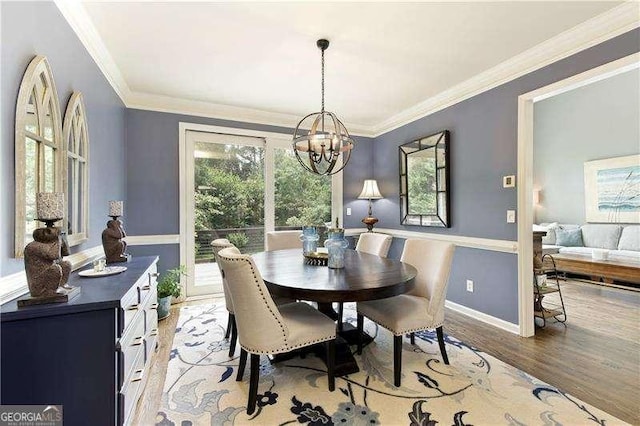 dining space with light wood finished floors, a chandelier, crown molding, and baseboards