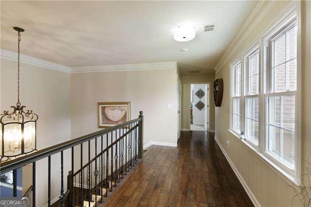 corridor featuring a chandelier, wood finished floors, ornamental molding, an upstairs landing, and baseboards