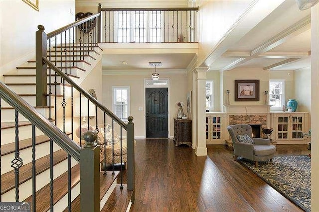 foyer featuring crown molding, wood finished floors, stairway, baseboards, and beam ceiling