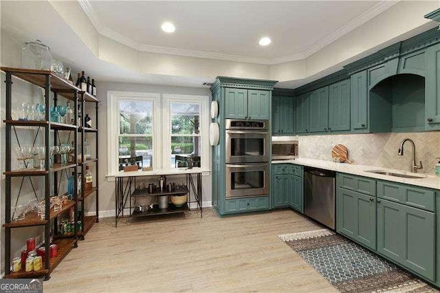 kitchen with appliances with stainless steel finishes, a sink, green cabinetry, crown molding, and recessed lighting