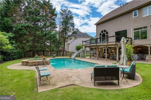 view of pool featuring a water slide, a patio, a wooden deck, and a pool with connected hot tub