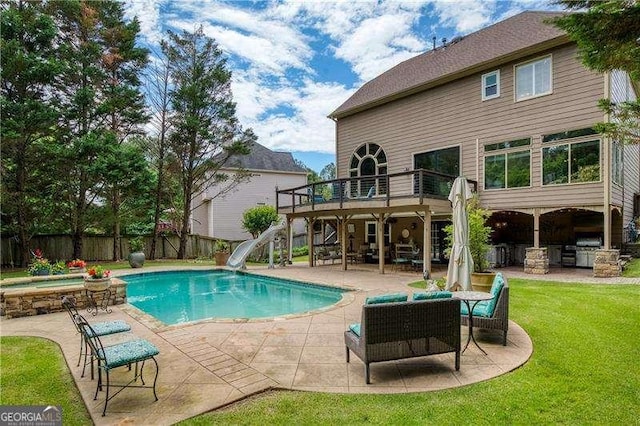 view of pool with a water slide, an in-ground hot tub, a patio, a wooden deck, and stairs