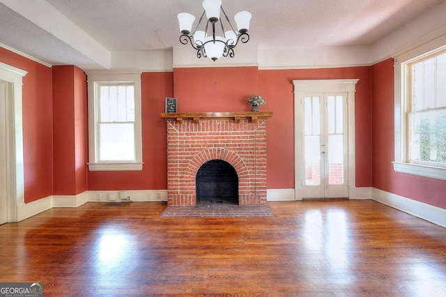 338 N Broad St, Monroe, GA 30655 - unfurnished living room featuring wood finished floors, a chandelier, a fireplace, and baseboards