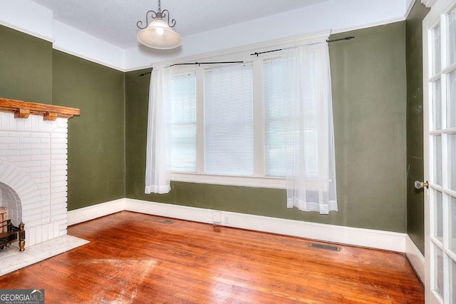 338 N Broad St, Monroe, GA 30655 - unfurnished living room with wood finished floors, baseboards, and a brick fireplace