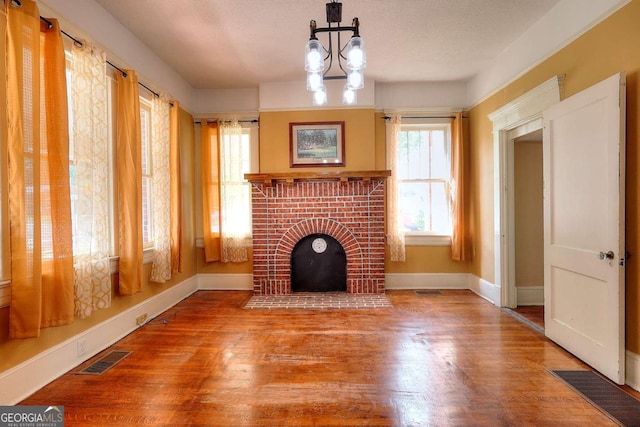 338 N Broad St, Monroe, GA 30655 - unfurnished living room with baseboards, a brick fireplace, wood finished floors, and a chandelier