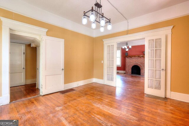 338 N Broad St, Monroe, GA 30655 - unfurnished dining area featuring french doors, wood finished floors, a chandelier, and baseboards