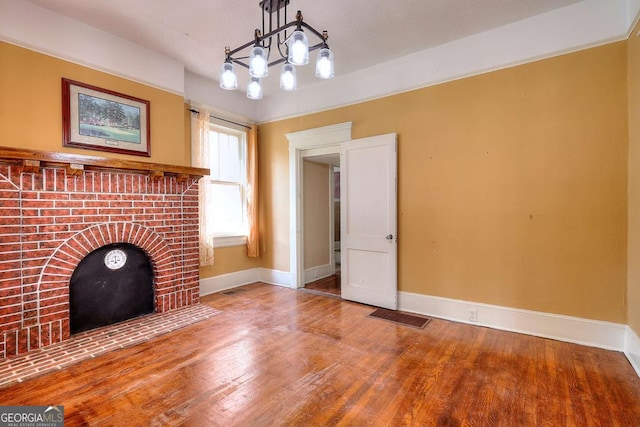 338 N Broad St, Monroe, GA 30655 - unfurnished living room with wood finished floors, baseboards, and a chandelier