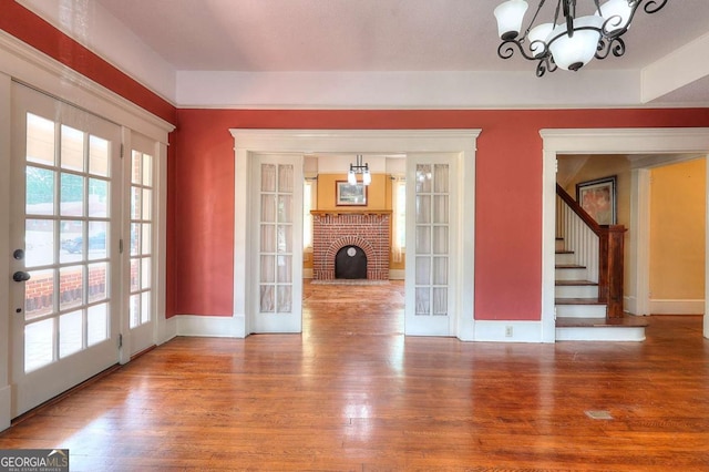 338 N Broad St, Monroe, GA 30655 - unfurnished living room with wood finished floors, baseboards, a chandelier, and a fireplace