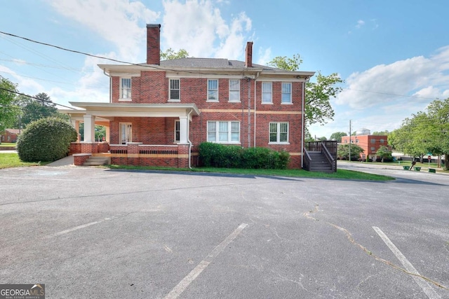 338 N Broad St, Monroe, GA 30655 - view of front of home with a chimney, brick siding, a porch, stairway, and uncovered parking