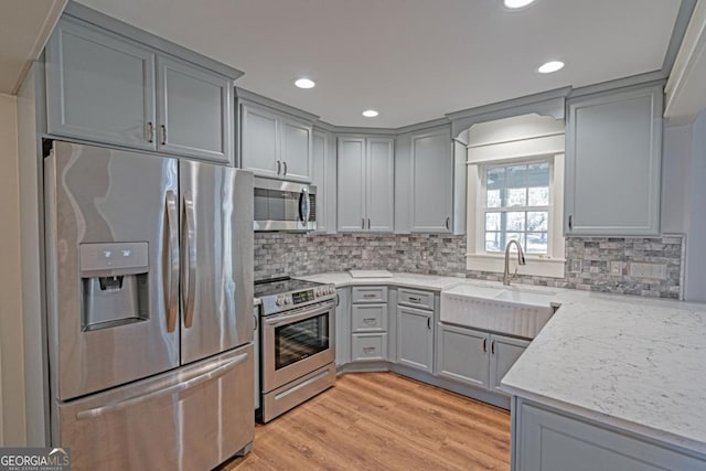 1443 Ebenezer Rd, Rincon, GA 31326 - kitchen featuring appliances with stainless steel finishes, gray cabinets, a sink, light stone counters, and backsplash
