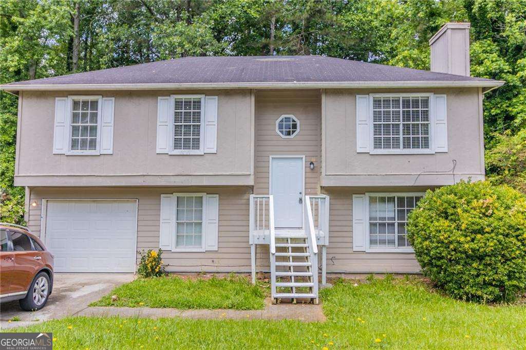 5339 Biffle Downs Rd, Stone Mountain, GA 30088 - bi-level home featuring an attached garage, a chimney, and driveway