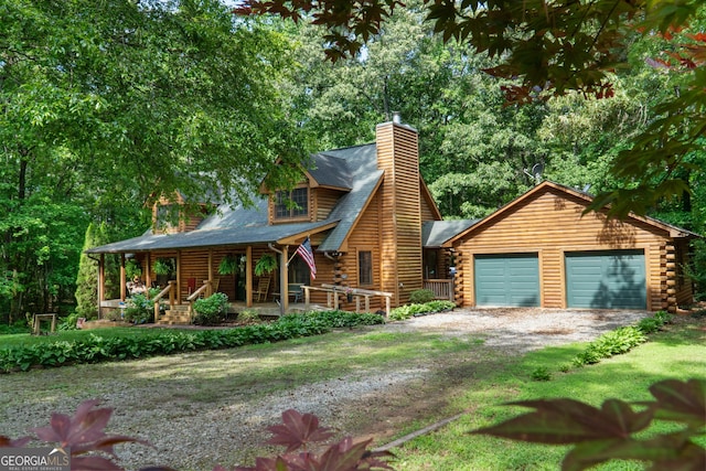 log cabin featuring log siding, driveway, a porch, and a chimney