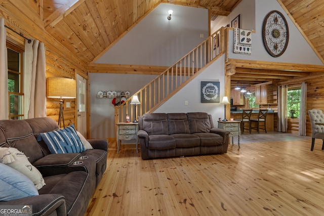living area with high vaulted ceiling, wood-type flooring, wooden ceiling, rustic walls, and stairway