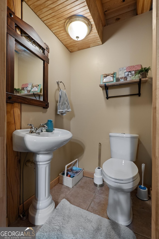 bathroom featuring toilet, baseboards, wooden ceiling, and tile patterned floors