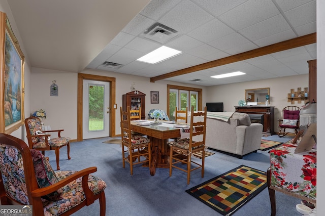 carpeted dining space with a drop ceiling