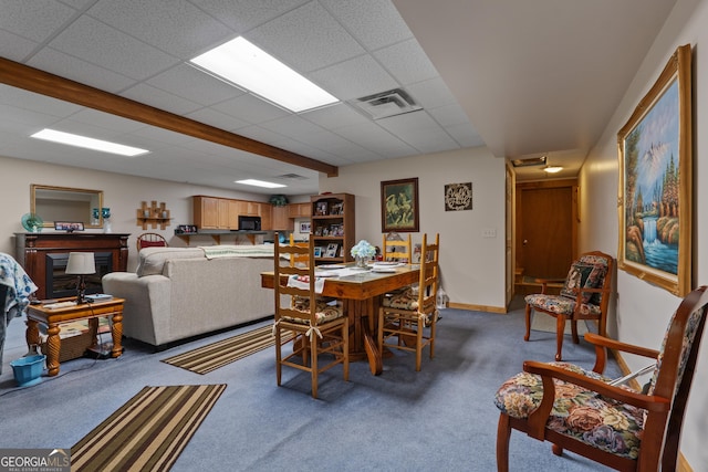 carpeted dining area featuring a drop ceiling and baseboards