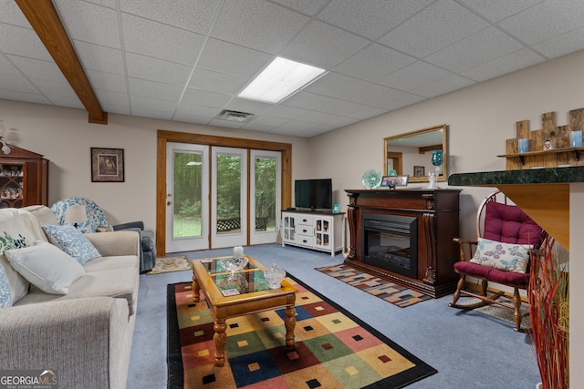 carpeted living area with a glass covered fireplace and a paneled ceiling