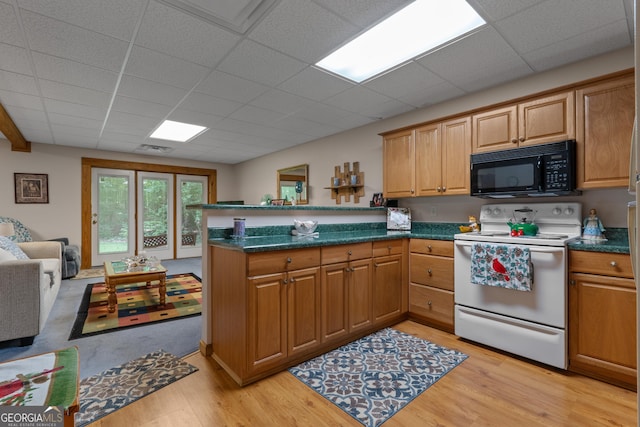kitchen featuring black microwave, electric stove, a peninsula, light wood-type flooring, and dark countertops