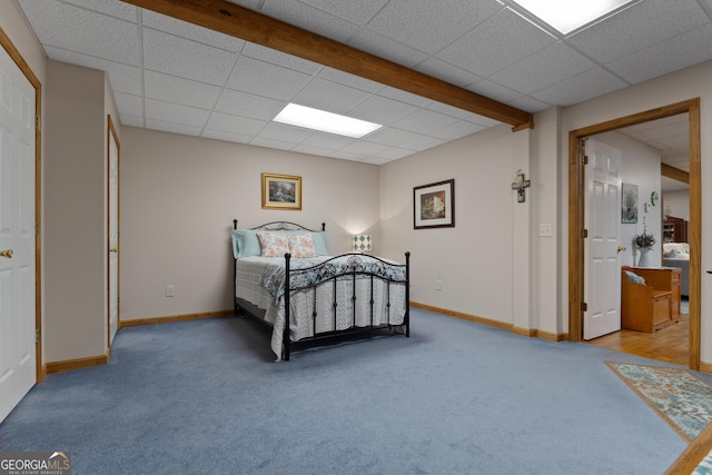 carpeted bedroom with a drop ceiling and baseboards