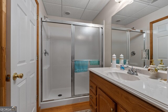 bathroom featuring a paneled ceiling, a stall shower, and vanity