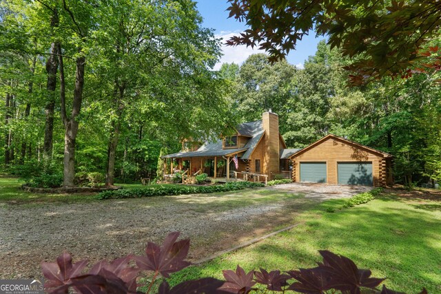 log home with a porch, a chimney, log siding, an outdoor structure, and a front yard