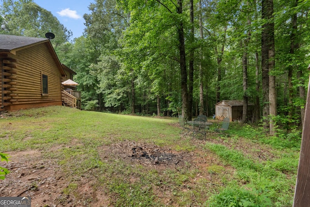 view of grassy yard with a storage shed, an outdoor structure, a deck, and a view of trees