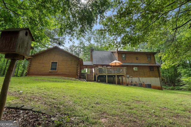 back of house with log exterior, a chimney, and a yard