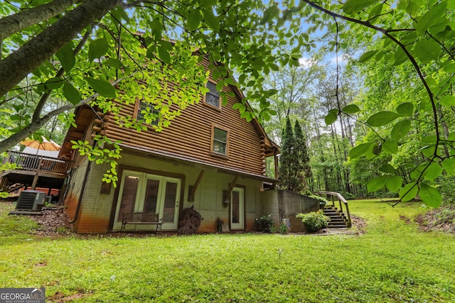rear view of house featuring log siding, a yard, central AC, stairs, and a wooden deck