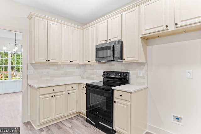 kitchen with black electric range, light wood finished floors, light countertops, backsplash, and a chandelier