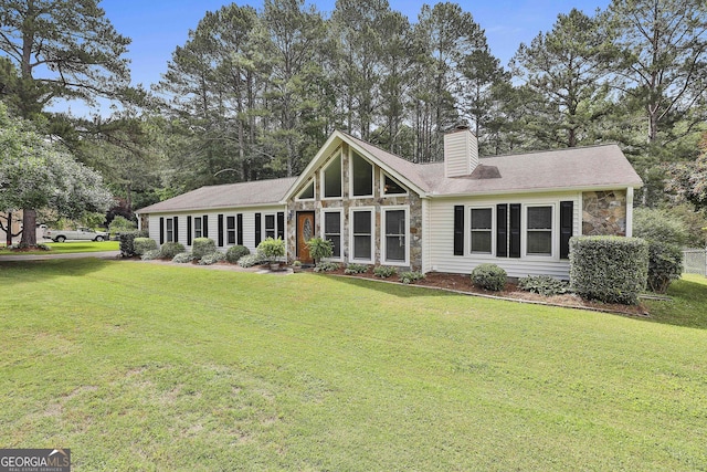 rear view of house featuring stone siding, a chimney, and a lawn