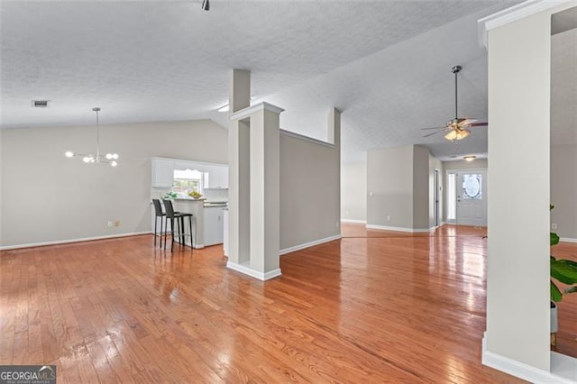 unfurnished living room with lofted ceiling, a ceiling fan, light wood finished floors, healthy amount of natural light, and a textured ceiling