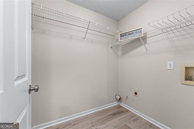 laundry area featuring electric dryer hookup, gas dryer hookup, hookup for a washing machine, wood finished floors, and baseboards