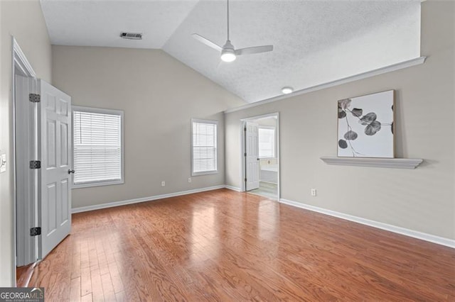 unfurnished bedroom with wood finished floors, baseboards, high vaulted ceiling, ceiling fan, and connected bathroom