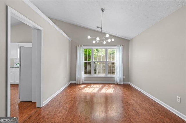 unfurnished dining area featuring lofted ceiling, wood finished floors, a chandelier, and baseboards