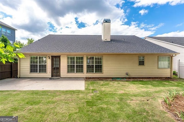 back of property with a chimney, a patio area, and roof with shingles