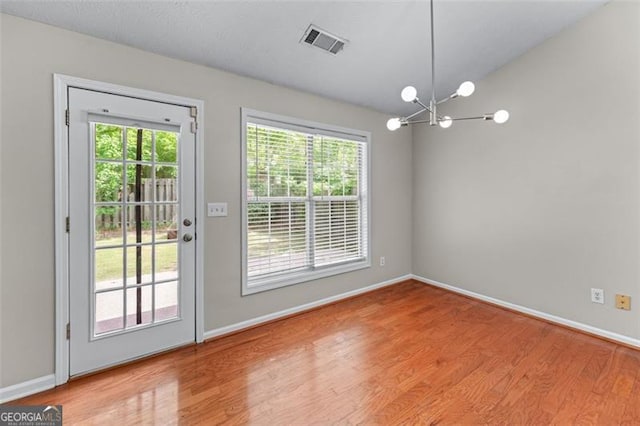 unfurnished dining area featuring wood finished floors, baseboards, and a chandelier
