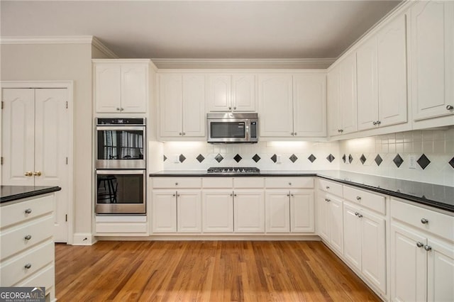 4045 Bonnett Creek Ln, Hoschton, GA 30548 - kitchen with stainless steel appliances, light wood-type flooring, white cabinetry, backsplash, and dark countertops
