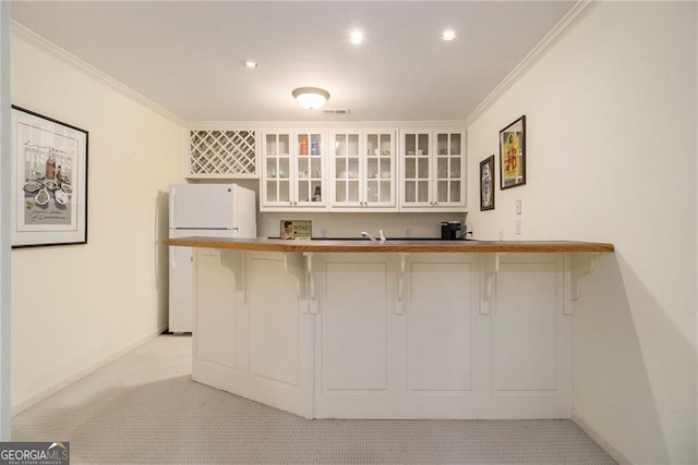 4045 Bonnett Creek Ln, Hoschton, GA 30548 - kitchen featuring freestanding refrigerator, a breakfast bar area, light colored carpet, crown molding, and glass insert cabinets