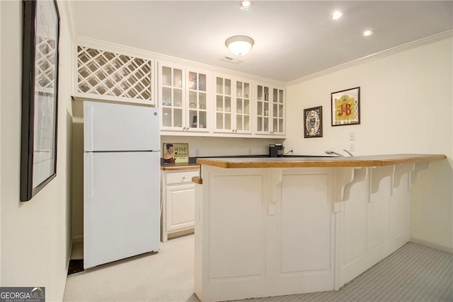 4045 Bonnett Creek Ln, Hoschton, GA 30548 - kitchen featuring freestanding refrigerator, light colored carpet, a kitchen bar, glass insert cabinets, and ornamental molding