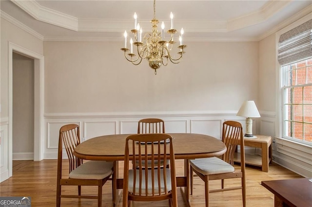 4045 Bonnett Creek Ln, Hoschton, GA 30548 - dining room featuring light wood finished floors, a chandelier, a tray ceiling, ornamental molding, and a wainscoted wall