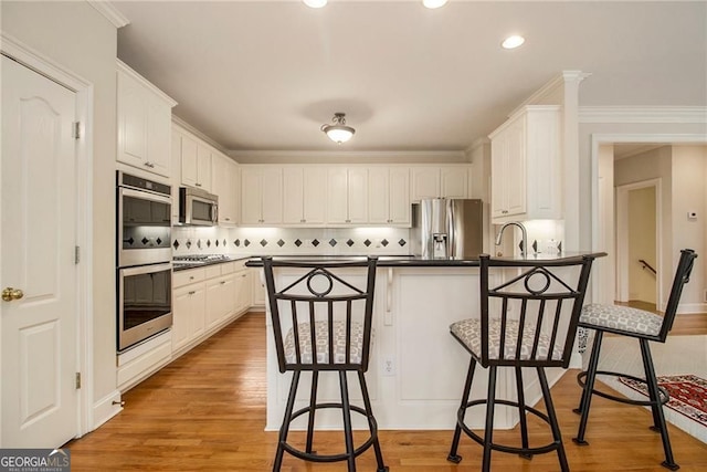 4045 Bonnett Creek Ln, Hoschton, GA 30548 - kitchen with appliances with stainless steel finishes, dark countertops, a breakfast bar, a peninsula, and white cabinets