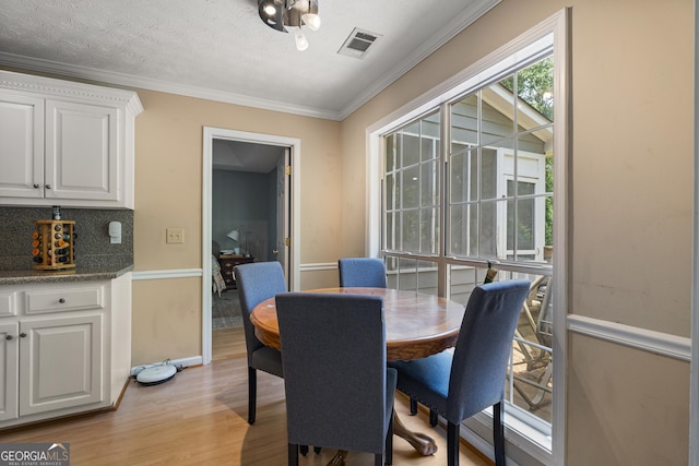 dining room featuring light wood finished floors, crown molding, and baseboards