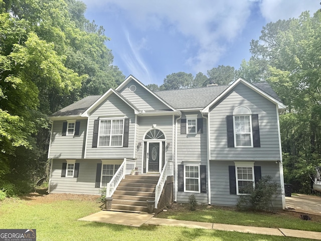 bi-level home featuring a front lawn and a shingled roof
