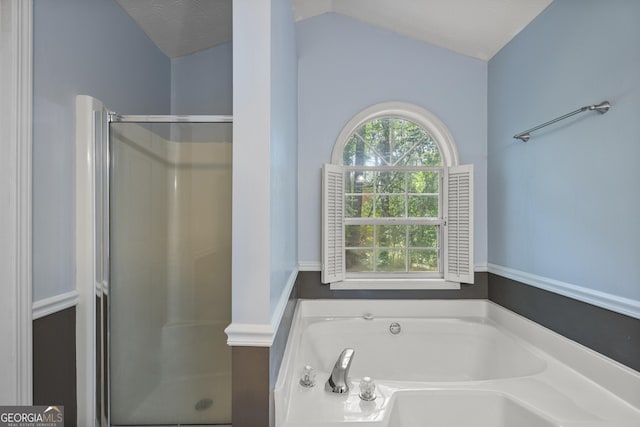 bathroom with a shower stall, lofted ceiling, and a garden tub