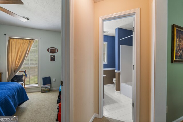 carpeted bedroom with connected bathroom, baseboards, and a textured ceiling